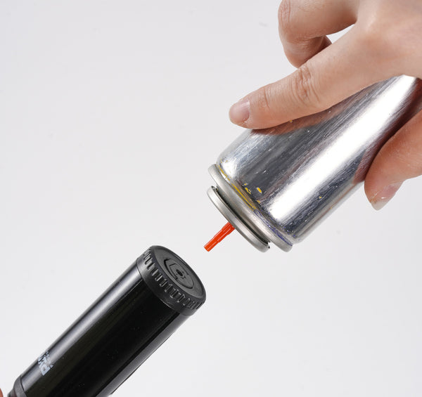 Refillable lighter being topped up upside down with butane gas
